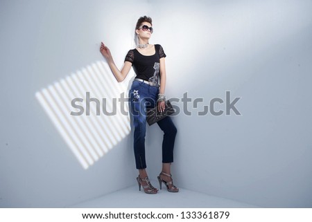 full-length portrait of a styled professional model wearing modern sunglasses holding purse Ã¢Â?Â?light background