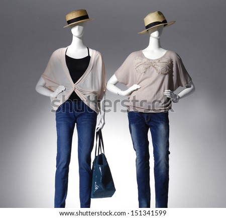 female clothing in hat with bag on two mannequin in light background