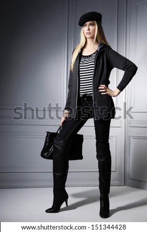 Full body portrait of fashion model holding bag posing in studio