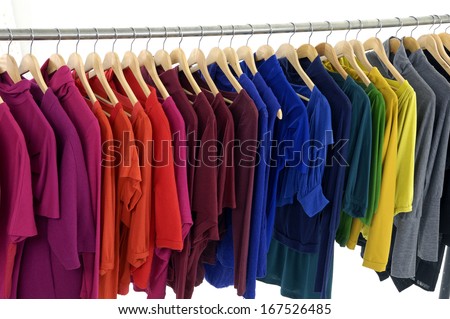 Variety of casual clothes of different colors on wooden hangers