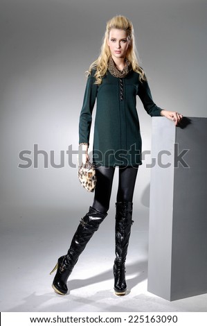 full-length Beautiful Young Model holding purse near wooden cube posing in light background