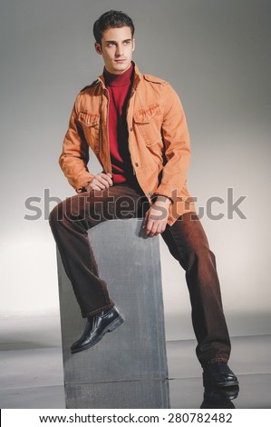 handsome young male model sitting cube - studio shoot