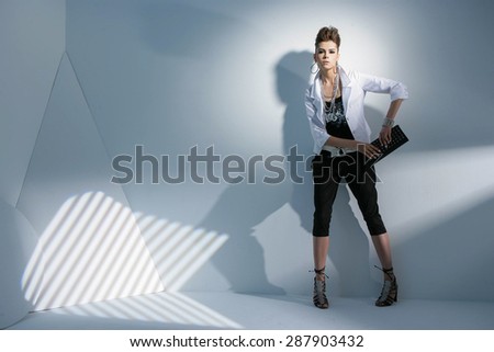 Full length portrait fashion model holding purse posing on light background