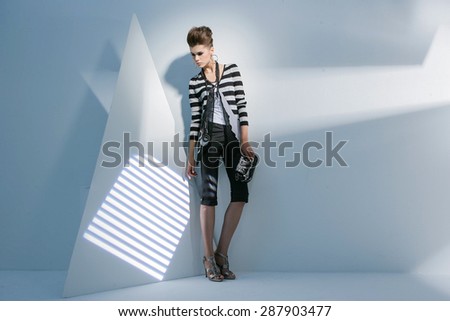 Full length portrait fashion model holding purse standing posing on light background