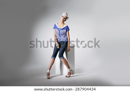 Full body Portrait of beautiful casual young fashion sitting cube model shot in studio