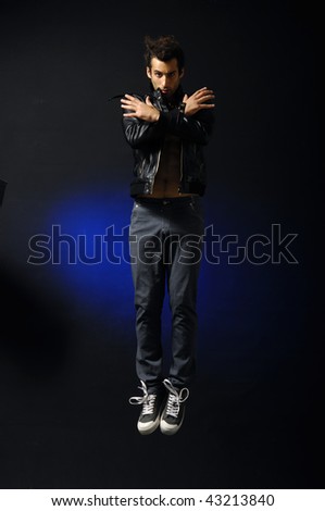 young man style jumping posing on blue light background