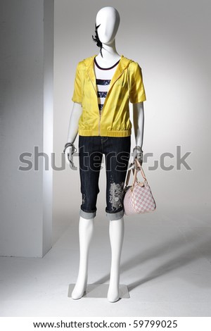 Fashion clothing on mannequin holding bag on light background