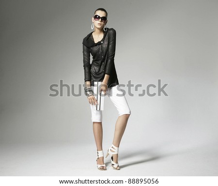 Full length fashion model holding little purse on light background