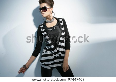 Vogue style fashion model wearing modern sunglasses posing on light background