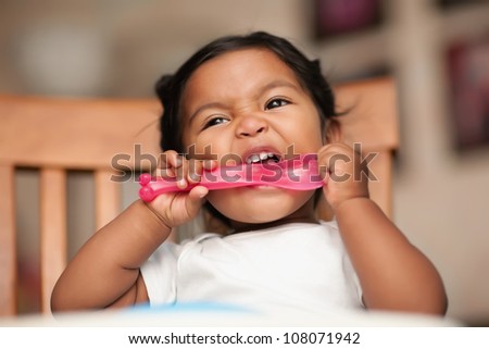 hungry baby putting a spoon to her mouth and biting it