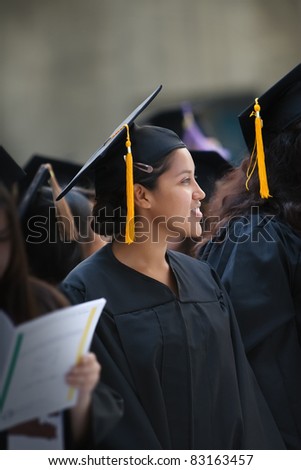 Hispanic woman wearing graduation hat and gown
