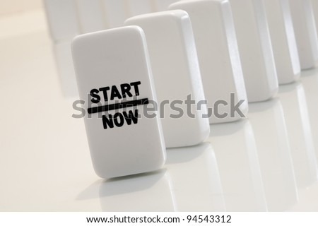 Start now message on aligned and standing dominoes