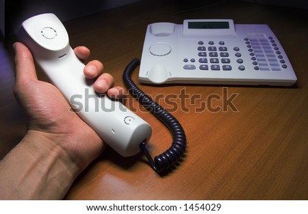telephone wiht handset in hands on brown table