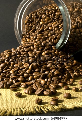 many Coffee beans in and out of a jar of glass