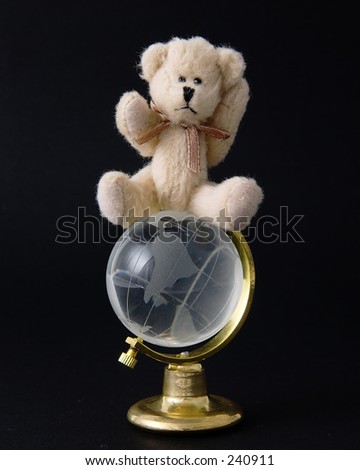 Teddy bear on top of the world isolated on a black background