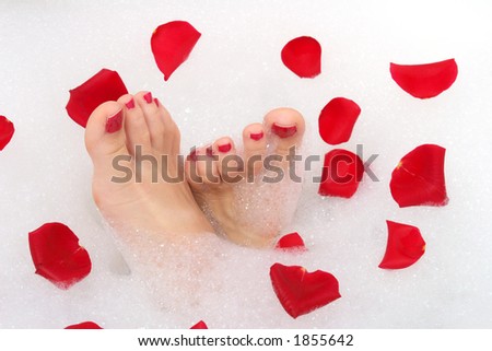 Feet and red rose petals in bath