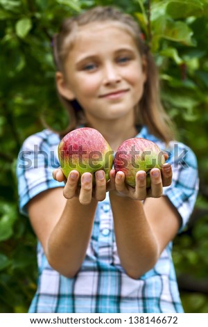 Smiling young girl collects the apples from tree. Apples in the foreground