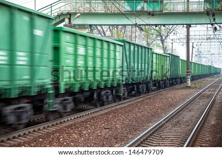 Freight train at fast speed in the movement under the bridge for pedestrians