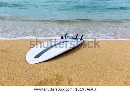 Fish Surfboard lying on sand on remote beach near the ocean