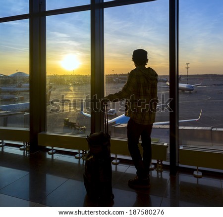 Silhouette of man with luggage standing near window in airport