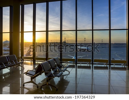 Silhouettes of bench in interior in airport lounge on background of the airfield with passenger planes