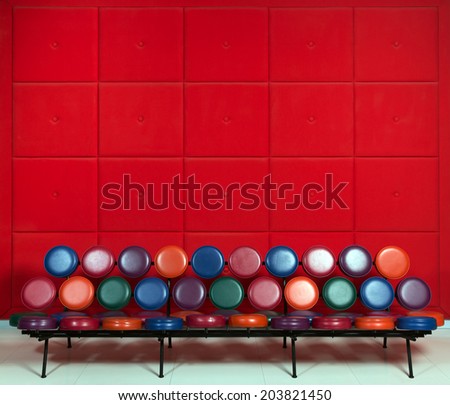 Colored metal bench in the lobby on a background of soft red walls