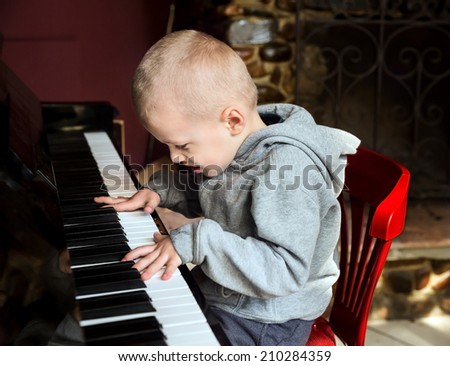 Emotional little boy learning to diligently play on the piano