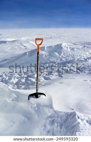 Snow shovel in fresh powder snow. Scenic landscape on the background of a snowy field in the mountains Elbrus