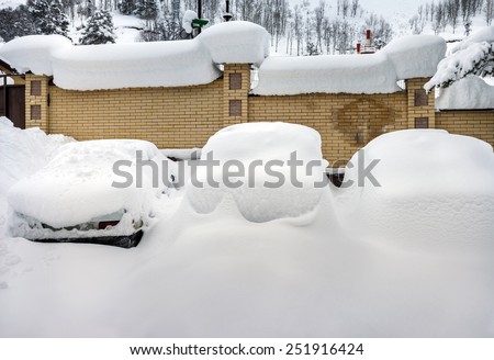 Cars covered with snow in the parking lot in rural mountain area