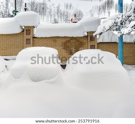 Cars covered with snow in the parking lot in rural mountain area