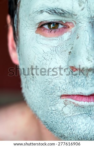 Men face closeup on facial blue clay mask. Treatment and care for the face skin