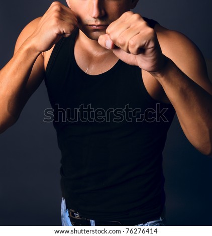 Muscular man in a boxing stance clenched fists. Shallow depth of field