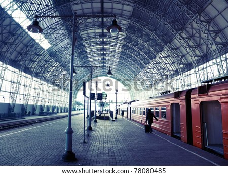 Covered old railway station with train and silhouettes of people