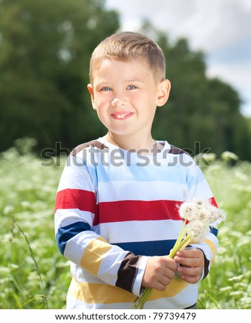 Beautiful boy  holds a dandelions in hands