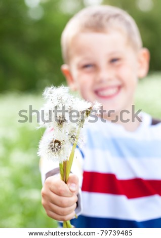 Beautiful boy  smiling and holds a dandelions in hands