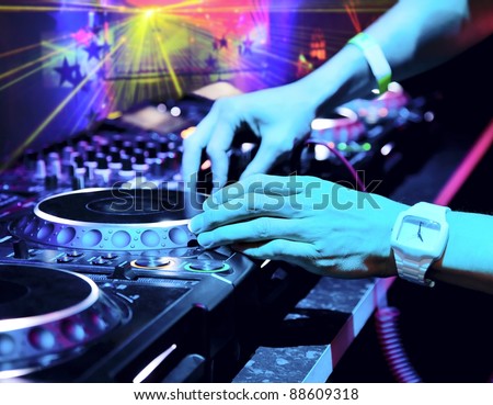 Dj mixes the track in the nightclub at a party. In the background laser light show