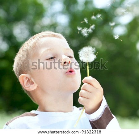 child blowing dandelion