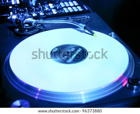 Dj mixes the track in the nightclub at a party. Vinyl Player in the foreground