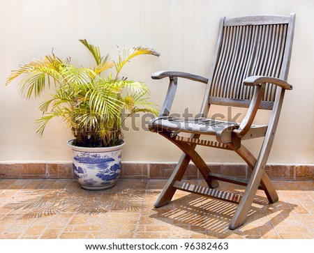 Stone terrace in the courtyard with wooden chair and palm tree in pot