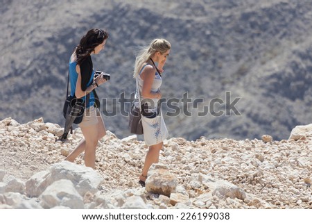 TEKIROVA, TURKEY - OCTOBER 7, 2009: Two young women climbing down the Tahtali Mountain on a small footpath. They are wearing light summer clothes and are poorly equipped for hiking in high mountains.