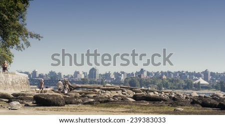 VANCOUVER, CANADA - AUGUST 5, 2005: Second Beach in Stanley Park with tourists climbing over driftwood in front of the skyline of Vancouver. Stanley Park is an urban park of more than 400 hectare.
