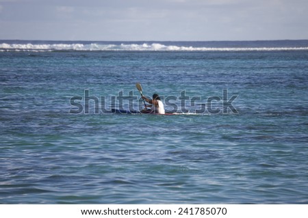 RAROTONGA, COOK ISLANDS - FEBRUARY 5, 2009: Man sea kayaking in tropical lagoon with coral reef of Rarotonga, Cook Islands, Polynesia.