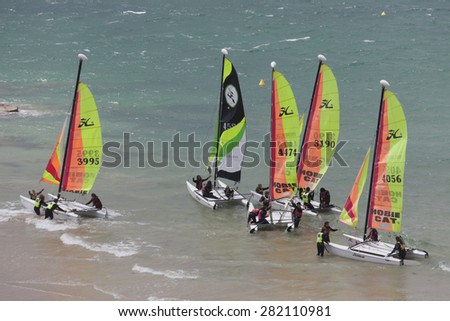 SAINT-MALO, FRANCE - JULY 6, 2011: Group of teenagers learning catamaran sailing on the coast of Saint-Malo. Their Hobie Cat 15 catamarans are 15 feet long and have a great buoyancy.