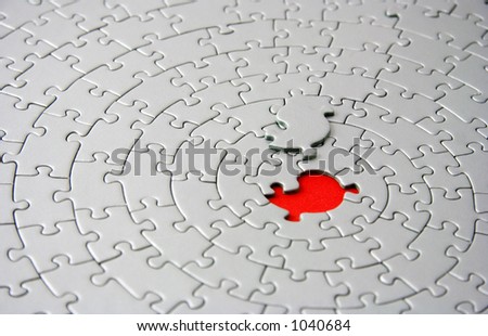 grey jigsaw with the missing piece laying above the red space - shallow DOF, focus is on the missing piece