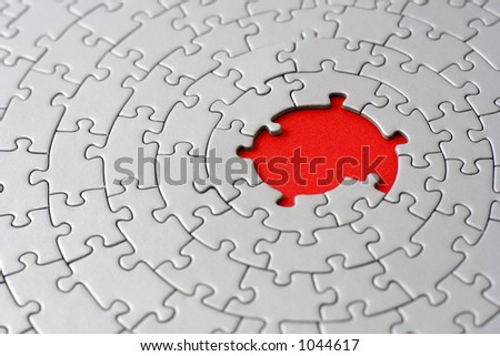 grey jigsaw with missing pieces in the red center - shallow DOF, focus is on the big hole