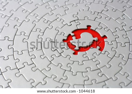 grey jigsaw with space and one of the missing pieces in the red center - pieces fitting together in form of a spiral
