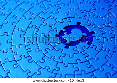 abstract of a blue jigsaw with space and one of the missing pieces in the center - pieces fitting together in form of a spiral