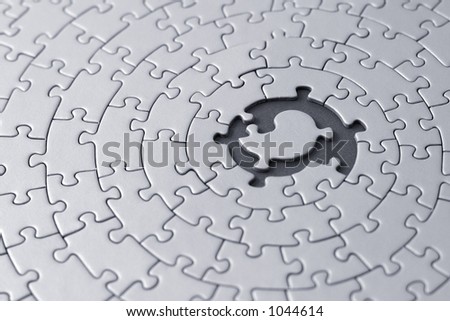 grey jigsaw with space and one of the missing pieces in the center - pieces fitting together in form of a spiral