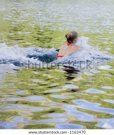 young woman swimming in a cold lake - with splashing water