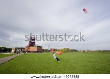 man with a power kite - action in an old industrial area with a shaft tower